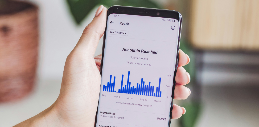 Someone holding a phone, showing Instagram insights - a key factor in social media management. 